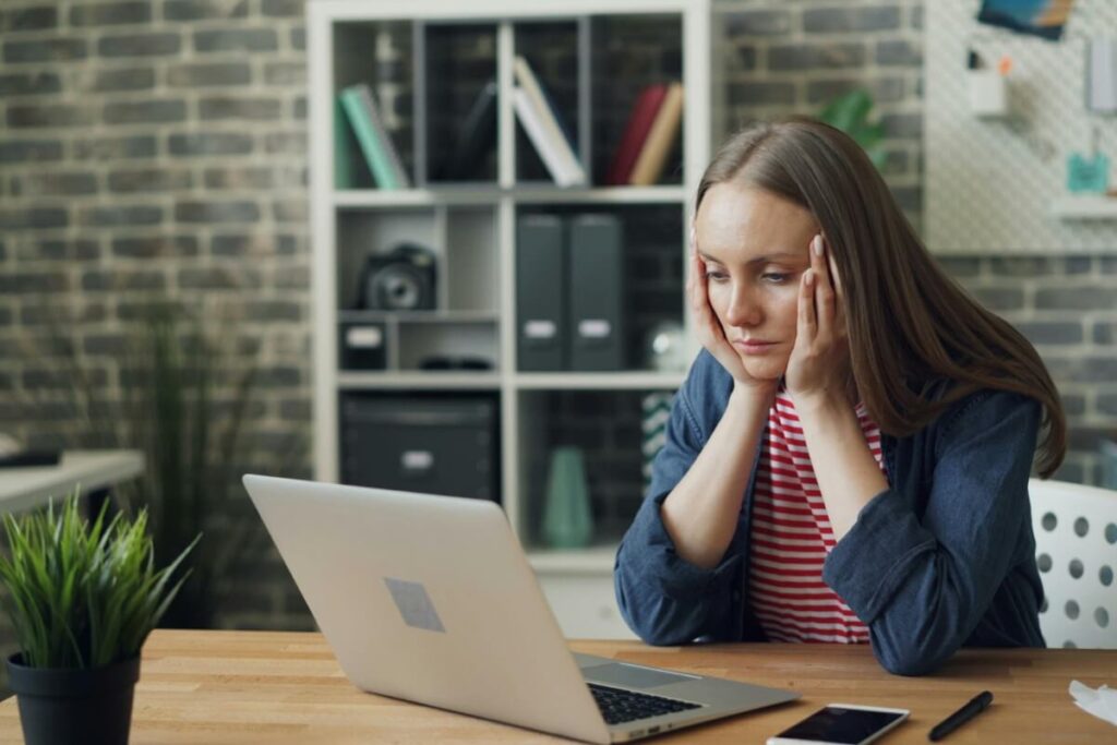 woman looking bemused. staring at a laptop wondering if her marketing budget is right